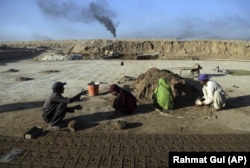 In this Wednesday, June 19, 2019, photo, Atiqullah, 30, right, and his son Kamran, 10, left, work at a brick factory on the outskirts of of Kabul, Afghanistan.