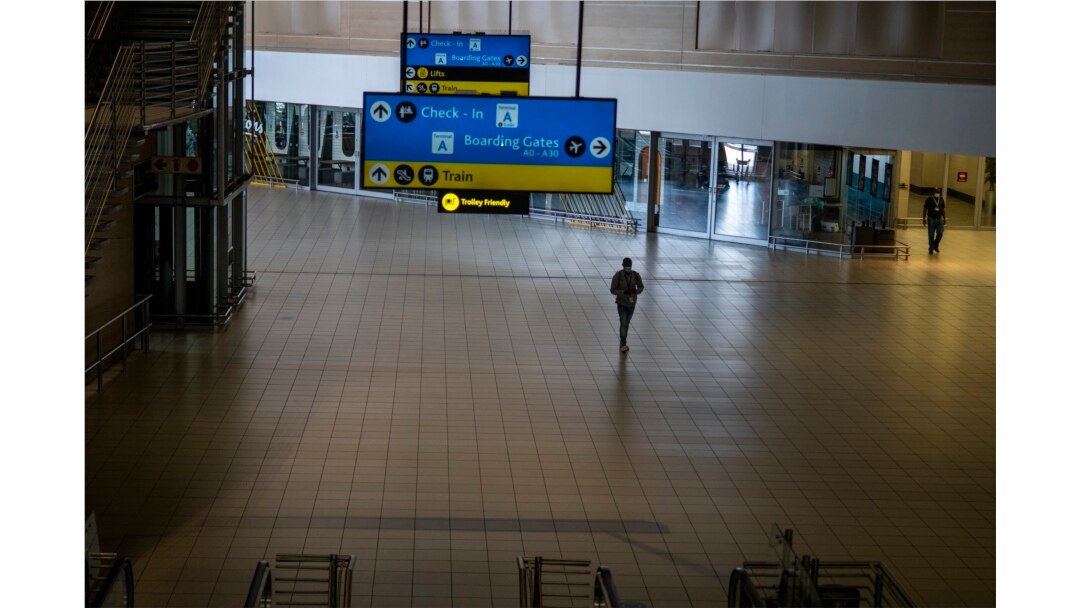 Seorang pria berjalan melalui bagian sepi bandara Johannesburg OR Tambo, Afrika Selatan, Senin 29 November 2021. (Foto: AP)