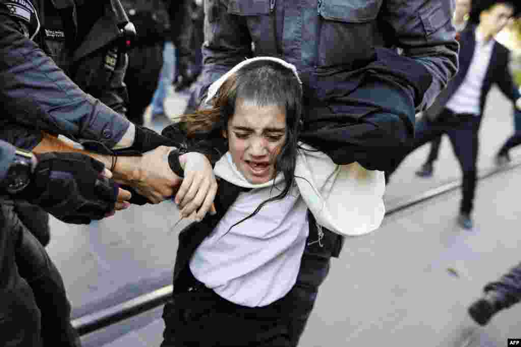 Israeli security forces grab an Ultra-Orthodox Jewish boy demonstrator blocking a main road as they disperse a protest against Israeli army conscription in the center of Jerusalem, Oct. 17, 2017.