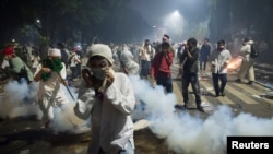  Muslim hardline protesters cover their faces as police fire tear gas during a protest against Jakarta's incumbent governor Basuki Tjahaja Purnama, an ethnic Chinese Christian running in the upcoming election, Nov. 4, 2016. The protests have put the country's president, Joko Widodo, in a tight spot.