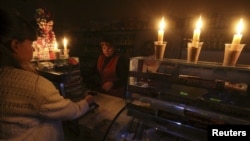 A customer visits a grocery lit with candles due to a power cut, in Simferopol, Crimea, Nov. 22, 2015. Electricity started flowing again on Dec. 8, 2015, along one of the four power lines destroyed by blasts during protests against Russia's annexation of Crimea.