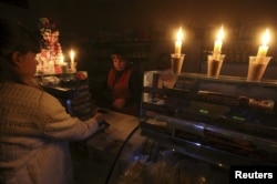 FILE - A customer visits a grocery lit with candles Nov. 22, 2015, due to a power cut, in Simferopol, Crimea.