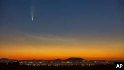 The Comet Neowise or C/2020 F3 is seen before sunrise over Balatonmariafurdo, Hungary, Tuesday, July 14, 2020. It passed closest to the Sun on July 3, and its closest approach to Earth will occur on July 23. (Gyorgy Varga/MTI via AP)