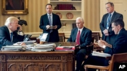 FILE - President Donald Trump, accompanied by, from second from left, Chief of Staff Reince Priebus, Vice President Mike Pence, White House press secretary Sean Spicer and National Security Adviser Michael Flynn, speaks on the phone with Russian President Vladimir Putin, Jan. 28, 2017, in the Oval Office at the White House in Washington.