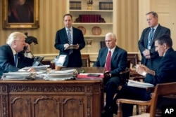 President Donald Trump accompanied by, from second from left, Chief of Staff Reince Priebus, Vice President Mike Pence, White House press secretary Sean Spicer and National Security Adviser Michael Flynn speaks on the phone with Russian President Vladimir