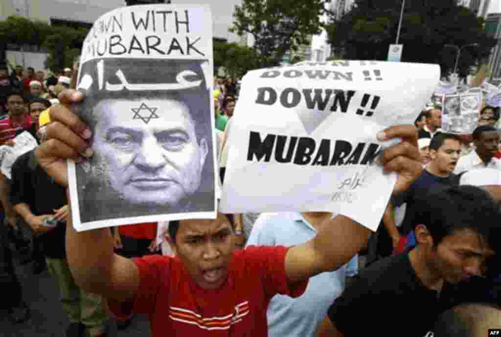A protester holds up a defaced photo of Egyptian President Hosni Mubarak and a slogan that reads "Down, down Mubarak" during a protest in front of U.S. Embassy in Kuala Lumpur, Malaysia, Friday, Feb. 4, 2011. More than 1,000 people protested outside the e