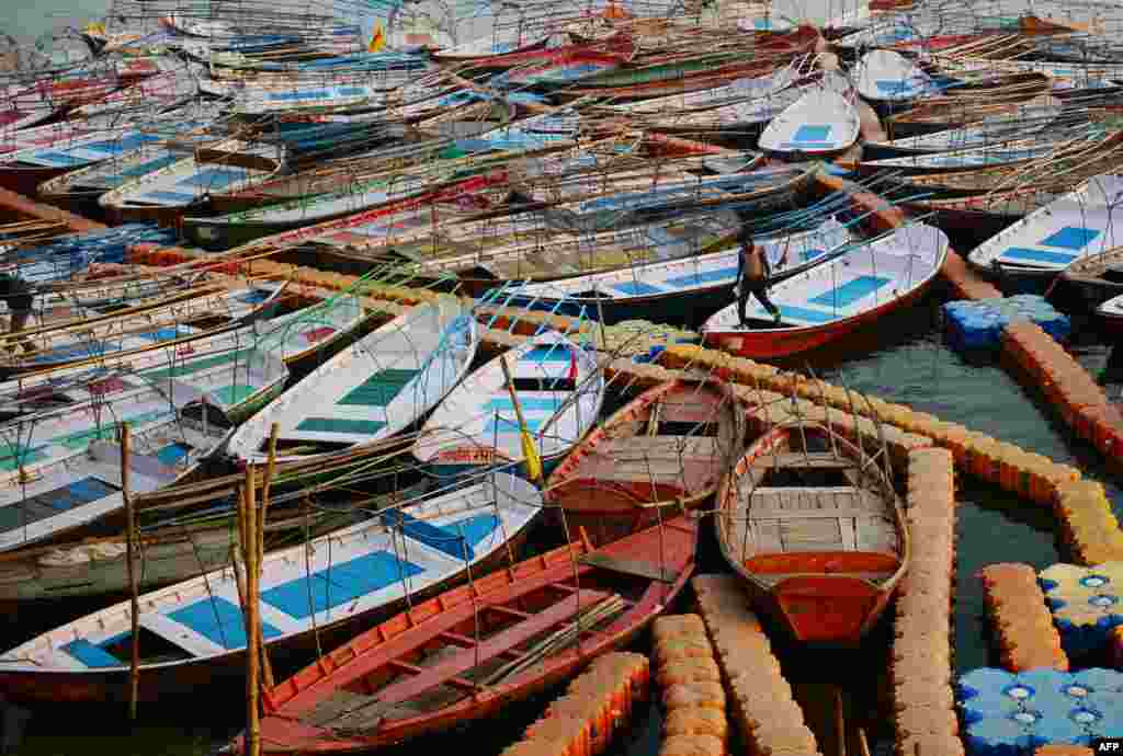 អ្នករត់ទូកម្នាក់ដើរកាត់ផែអណ្តែតដែលធ្វើពីផ្លាស្ទិកនៅក្បែរច្រាំងទន្លេ Yamuna ក្នុងទីក្រុង Allahabad ប្រទេសឥណ្ឌា។