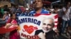 A supporter holds up an America Loves Modi sign as he assembles with a large crowd of people in Times Square to watch the speech by India's Prime Minister Narendra Modi simulcast in New York, Sept. 28, 2014. 