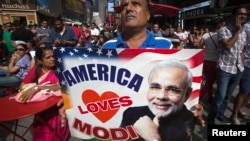 A supporter holds up an America Loves Modi sign as he assembles with a large crowd of people in Times Square to watch the speech by India's Prime Minister Narendra Modi simulcast in New York, Sept. 28, 2014. 