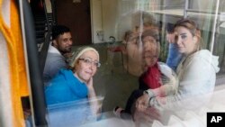 Boshra al-Moallem, bottom left, looks out of the window as she sits in a room with her two sisters and brother-in-law at a refugee center in Bialystok, Poland, Sept. 29, 2021.