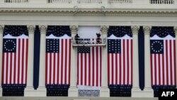 Two workers adjust U.S. flags on the Capitol as preparations continue for the second inauguration of President Barack Obama in Washington, D.C., January 17, 2013. 