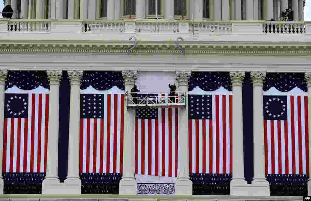 Two workers adjust U.S. flags on the Capitol as preparations continue for the second inauguration of President Barack Obama in Washington, D.C., January 17, 2013.