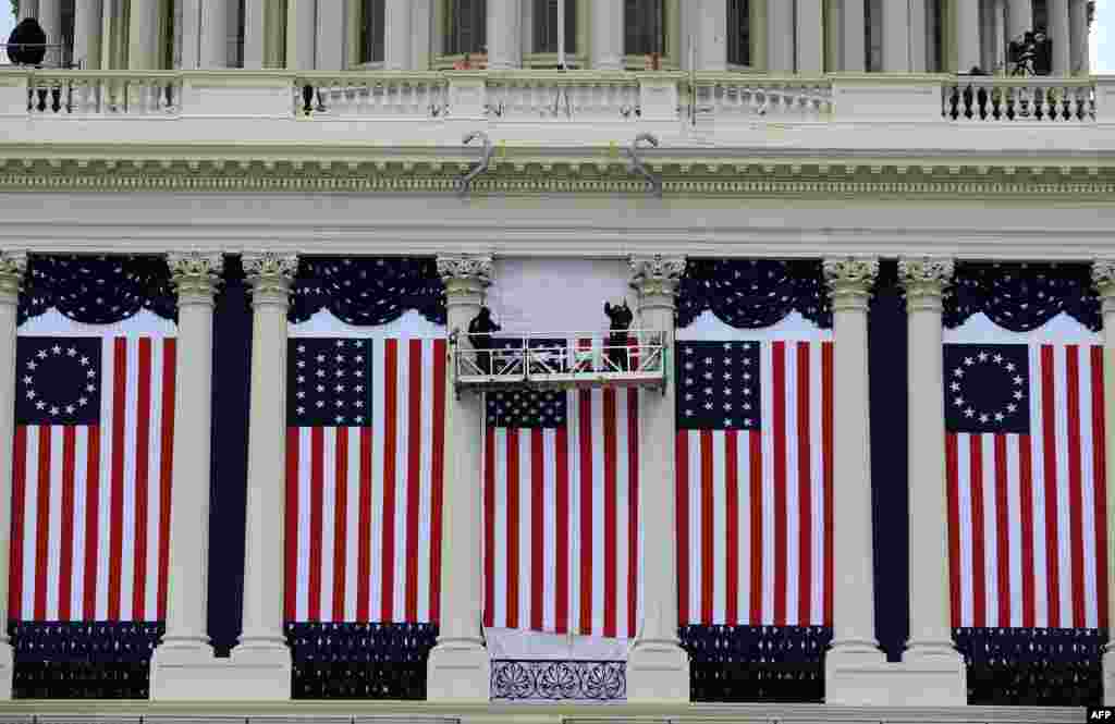 Deux personnes ajustant le drapeau am&eacute;ricain lors des pr&eacute;paratifs de la c&eacute;r&eacute;monie d&#39;investiture du Pr&eacute;sident Barack Obama,&nbsp; Washington, D.C., 17 janvier, 2013. 