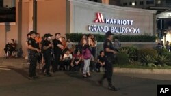 Armed security officers and onlookers gather outside a hotel at the Resorts World Manila complex, early Friday, June 2, 2017, in Manila, Philippines. 