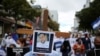 Un hombre sostiene una cruz de madera con una foto del estudiante de 24 años Tony Merlo Sevilla, quien fue asesinado por las fuerzas nicaragüenses durante las protestas antigubernamentales. Noviembre 7 de 2021.