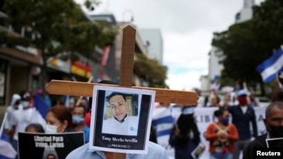 Un hombre sostiene una cruz de madera con una foto del estudiante de 24 años Tony Merlo Sevilla, quien fue asesinado por las fuerzas nicaragüenses durante las protestas antigubernamentales. Noviembre 7 de 2021.