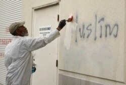 A man paints over racist graffiti, which included such pronouncements as "Muslims out," on the side of a mosque in what officials are calling an apparent hate crime, in Roseville, California, Feb. 1, 2017.