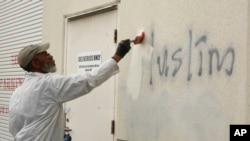 A man paints over racist graffiti, which included such pronouncements as "Muslims out," on the side of a mosque in what officials are calling an apparent hate crime, in Roseville, California, Feb. 1, 2017.