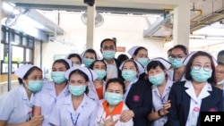 ကိုရိုနာဗိုင်းရပ်စ် ကူးစက်မှု ကာကွယ်နိုင်ရေး နှာခေါင်းစည်းများ တပ်ဆင်ထားသည့် ထိုင်းဝန်ကြီးချုပ်နှင့် ဘန်ကောက်မြို့ Rajavithi ဆေးရုံမှ သူနာပြုများ။ (မတ် ၁၂၊ ၂၀၂၀)