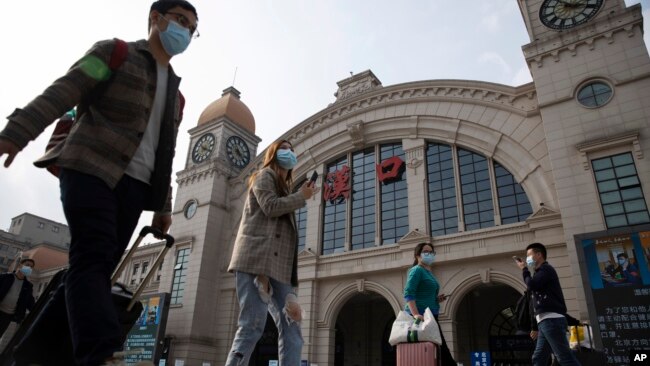 2020年4月7日武汉恢复交通前夕，带着行李的旅客走过汉口火车站。