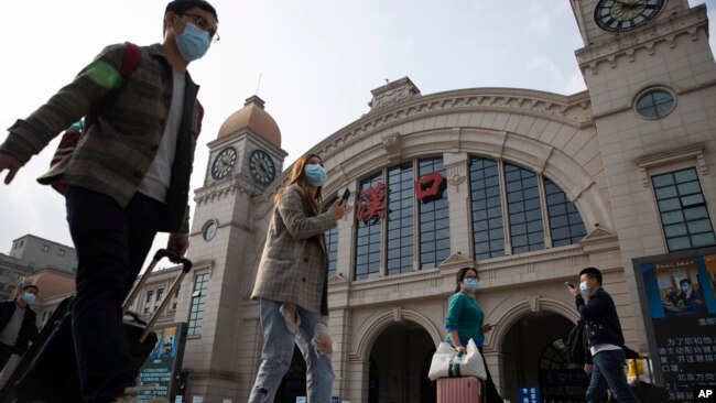 2020年4月7日武汉恢复交通前夕,带着行李的旅客走过汉口火车站。