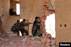 FILE - Kurdish People's Protection Units (YPG) fighters take up positions inside a damaged building in al-Vilat al-Homor neighborhood in Hasaka city, as they monitor the movements of Islamic State fighters stationed in Ghwayran neighborhood.