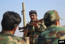 Abbas Hamza Hassan, a 56-year-old Iraqi fighter who in 2014 left the southern Iraqi province of Basra to join the forces of the paramilitary units of the Hashed Shaabi (Popular Mobilization) against Islamic State group (IS), is pictured on Nov. 13, 2018, while training fellow Hashed members on using weapons in al-Qaim in the western Iraqi province of Anbar, along the border with Syria.