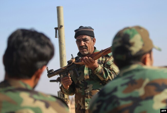 Abbas Hamza Hassan, a 56-year-old Iraqi fighter who in 2014 left the southern Iraqi province of Basra to join the forces of the paramilitary units of the Hashed Shaabi (Popular Mobilization) against Islamic State group (IS), is pictured on Nov. 13, 2018, while training fellow Hashed members on using weapons in al-Qaim in the western Iraqi province of Anbar, along the border with Syria.