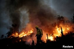 FILE - A Brazilian Institute for the Environment and Renewable Natural Resources (IBAMA) fire brigade member attempts to control a fire in a tract of the Amazon jungle in Apui, Amazonas State, Brazil, August 11, 2020. (REUTERS/Ueslei Marcelino)