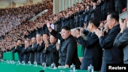ຜູ້ນຳເກົາຫຼີເໜືອ ທ່ານ Kim Jong Un ໂບກມືທັກທາຍ ໃນລະຫວ່າງ ການແຂ່ງຂັນເຕາະບານຊາຍ ລະຫວ່າງ ທິມ Sonbong ແລະ Hwoebul ສຳຫລັບລາງວັນເກມກີລາ Mangyongdae ຢູ່ທີ່ສະໜາມກີລາ Kim Il Sung ໃນຮູບພາບທີ່ເປີດເຜີຍໂດຍ ອົງການ​ຂ່າວ​ສູນກາງຂອງທາງ​ການ​ເກົາຫຼີເໜືອ ທີ່ບໍ່ໄດ້ລະບຸວັນເວລາ, ວັນທີ 14 ເມສາ 2015. 