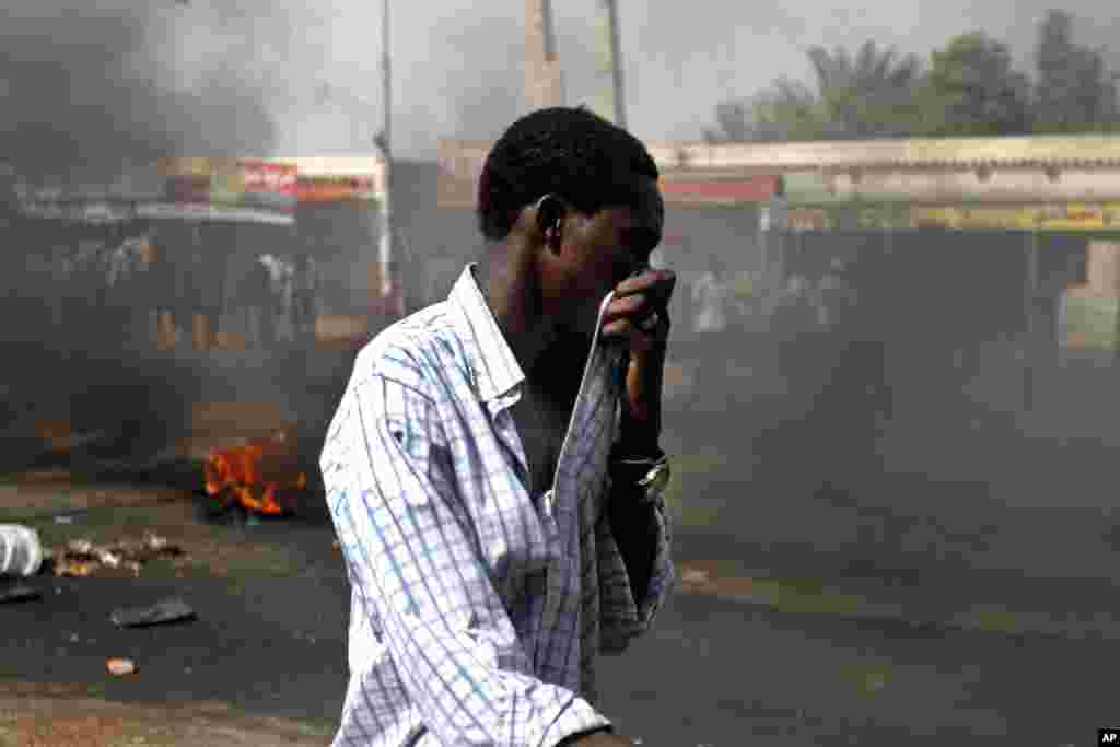 9月25日在苏丹卡德罗，一名苏丹男子用手捂着嘴，以防吸入浓烟。