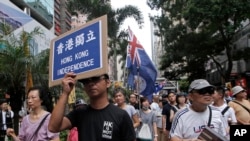 Protesters hold placards and wave Hong Kong colonial flags during the annual pro-democracy protest in Hong Kong. As the Asian financial center prepares for legislative elections in September.