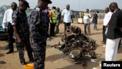 Air Commodore Charles Otegbade (3rd L), director of search and rescue operations, looks at the wreckage after a bomb blast at Nyayan bus terminal in Abuja, April 14, 2014.