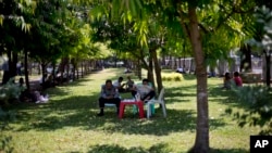 دھوپ کی شدت سے بچنے کے لیے رنگون کے ایک پارک میں لوگ درختوں کی چھاؤں تلے بیٹھے ہیں۔ فائل فوٹو