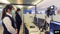 台灣疾病控制中心的工作人員在台北桃園國際機場檢測從中國武漢抵達的乘客的體溫。（2020年1月13日） 