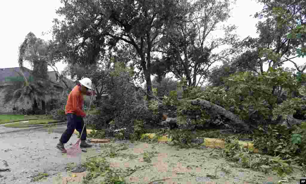 A man cleans up debris from trees knocked down by Hurricane Harvey, in Missouri City, Texas, Aug. 26, 2017.