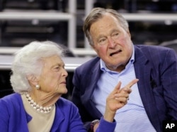 FILE - Former president George H.W. Bush and his wife, Barbara Bush, are seen at a college basketball game in Houston, Texas, March 29, 2015.