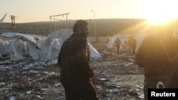 Residents and Free Syrian Army fighters are seen near damaged tents for Syrian refugees after shelling by forces loyal to Syria's President Bashar al-Assad on the outskirts of Idlib, near the Syrian-Turkey border, November 26, 2012.