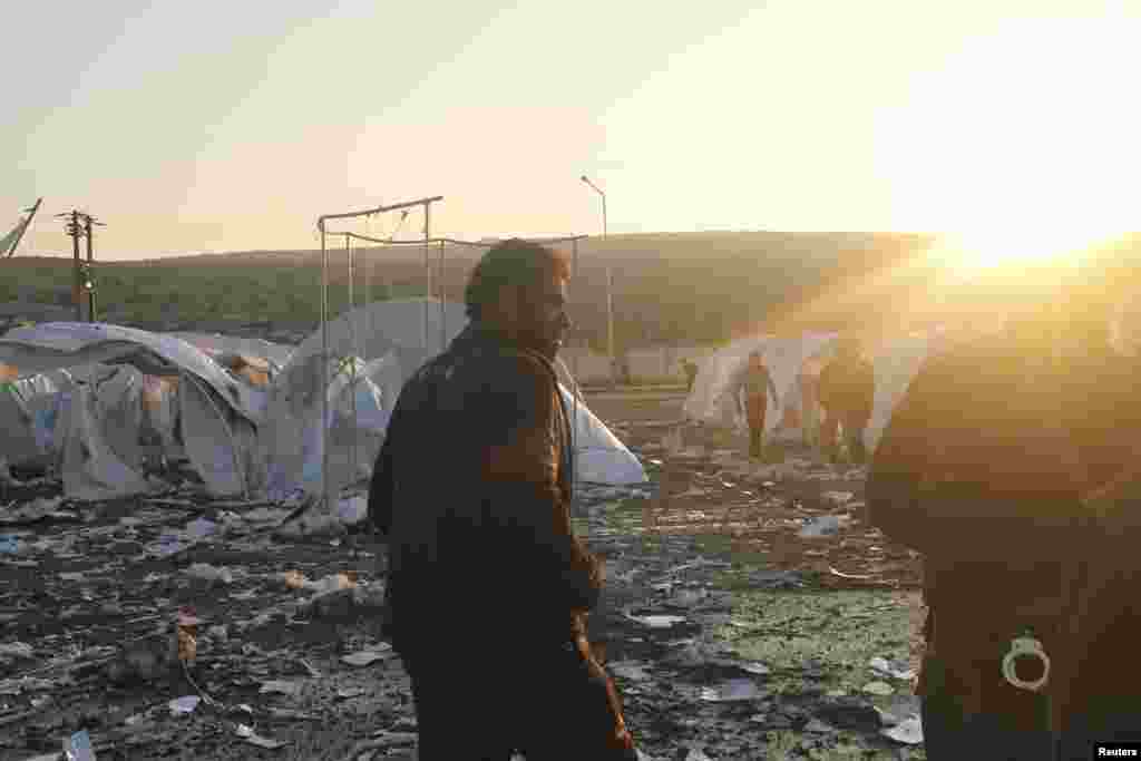 Residents and Free Syrian Army fighters are seen near damaged tents for Syrian refugees after shelling by forces loyal to Syria's President Bashar al-Assad on the outskirts of Idlib, near the Syrian-Turkey border, November 26, 2012.