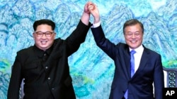 North Korean leader Kim Jong Un, left, and South Korean President Moon Jae-in raise their hands after signing a joint statement at the border village of Panmunjom in the Demilitarized Zone, South Korea, April 27, 2018.