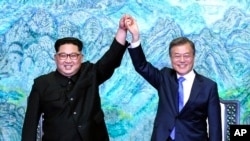 North Korean leader Kim Jong Un, left, and South Korean President Moon Jae-in raise their hands after signing a joint statement at the border village of Panmunjom in the Demilitarized Zone, South Korea, April 27, 2018.