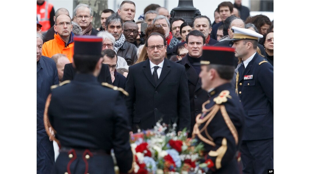 France's President Francois Hollande, left, and Prime Minister Manuel Valls, right, lay a wreath of flowers at Place de la Republique in Paris during a ceremony to honor the victims of the Islamic extremist attacks, Jan. 10, 2016.