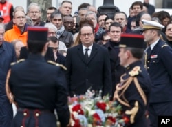 France's President Francois Hollande, left, and Prime Minister Manuel Valls, right, lay a wreath of flowers at Place de la Republique in Paris during a ceremony to honor the victims of the Islamic extremist attacks, Jan. 10, 2016.