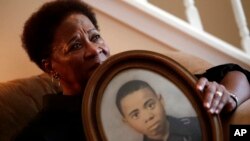 In this Aug. 9, 2018 photo, Eberlene King poses with a photograph of her brother William Roy Prather when he was about 15 years old at her home in Doraville, Georgia.