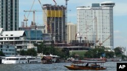 FILE - A riverboat taxi crosses the Chao Phraya river in front of massive construction projects, Jan. 18, 2017, in Bangkok, Thailand. 