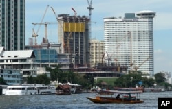 FILE - A riverboat taxi crosses the Chao Phraya river in front of massive construction projects, Jan. 18, 2017, in Bangkok, Thailand.