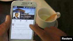 FILE - A person uses a smartphone to look at the Facebook page of Cambodia's Prime Minister Hun Sen, in central Phnom Penh, Cambodia Oct. 7, 2015. Cambodia's Prime Minister Hun Sen is taking a belated leap into the digital age.