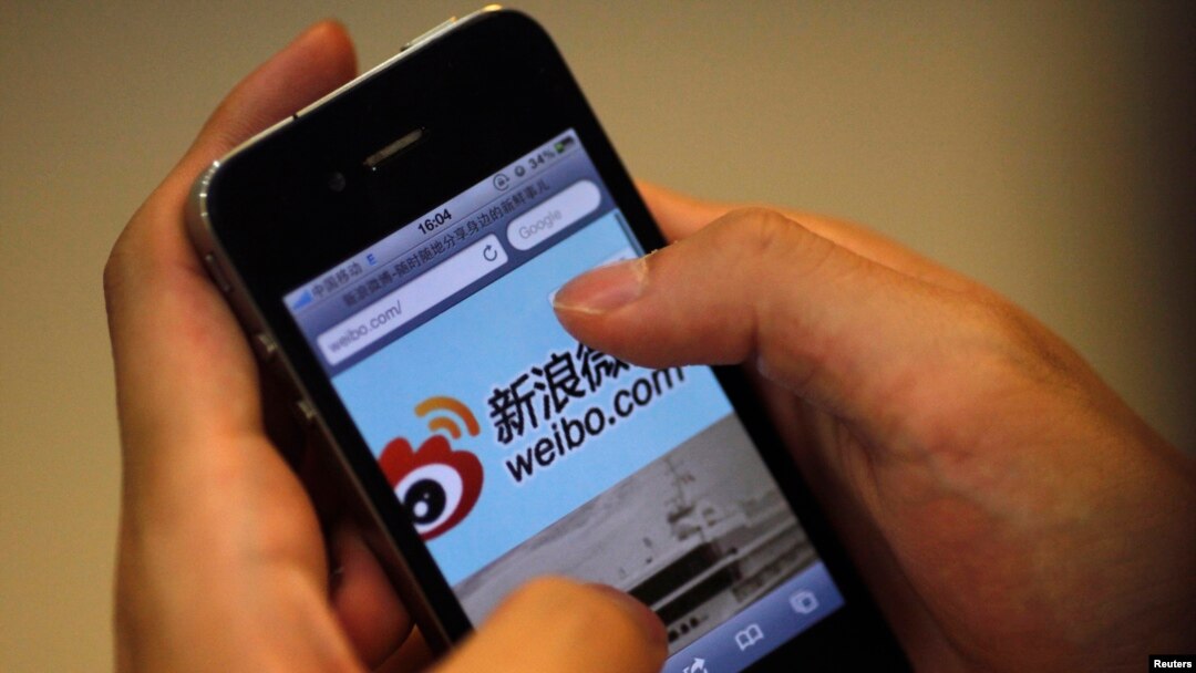 A man holds an iPhone as he visits Sina's Weibo microblogging site in Shanghai May 29, 2012.