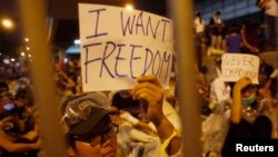 Protesters hold up signs during an evening rally attended by thousands in front of the government headquarters in Hong Kong, Sept. 27, 2014. 