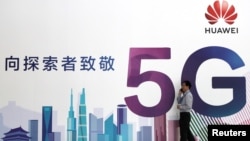 一名男子走過在北京舉辦的中國國際信息通訊展覽會的一塊華為公司5G技術廣告牌。（2018年9月26日） 